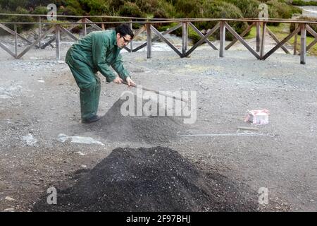 Ein Mann, der ein Loch in Fumarolis da Lagoa das Furnas für Cozido das Furnas auf der Insel Sao Miguel auf den Azoren, Portugal, grub Stockfoto