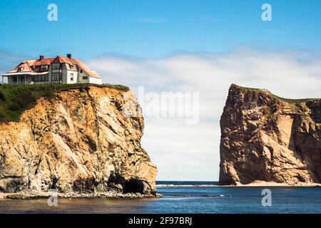 Ein Haus auf einer der riesigen, schieren Felsformationen im Golf von St. Lawrence an der Spitze der Gaspé-Halbinsel in Québec, Kanada. Stockfoto