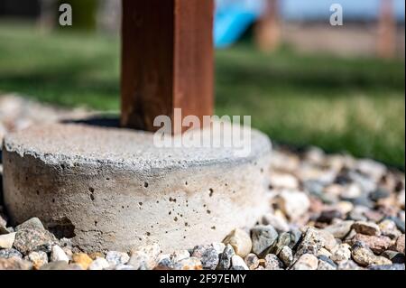 Betonrohrfuß, der verwendet wird, um die Stütze von einem abgehängten Holzdeck auf ein festes Fundament unterhalb der Frostlinie zu übertragen. Stockfoto