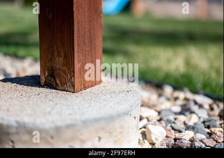 Betonrohrfuß, der verwendet wird, um die Stütze von einem abgehängten Holzdeck auf ein festes Fundament unterhalb der Frostlinie zu übertragen. Stockfoto