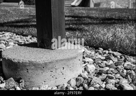 Betonrohrfuß, der verwendet wird, um die Stütze von einem abgehängten Holzdeck auf ein festes Fundament unterhalb der Frostlinie zu übertragen. Stockfoto