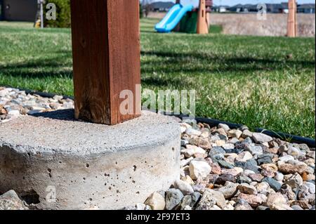 Betonrohrfuß, der verwendet wird, um die Stütze von einem abgehängten Holzdeck auf ein festes Fundament unterhalb der Frostlinie zu übertragen. Stockfoto