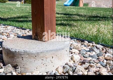 Betonrohrfuß, der verwendet wird, um die Stütze von einem abgehängten Holzdeck auf ein festes Fundament unterhalb der Frostlinie zu übertragen. Stockfoto