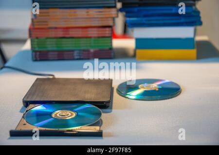 Kompakter, eleganter Video-Player für CD- und DVD-Discs mit Ein Haufen von vielen TV-Serien-Film-Discs im Hintergrund Stockfoto