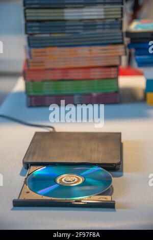Kompakter, eleganter Video-Player für CD- und DVD-Discs mit Ein Haufen von vielen TV-Serien-Film-Discs im Hintergrund Stockfoto