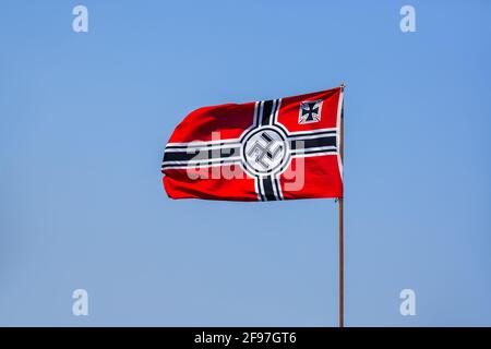 Die deutsche Nazi-Flagge winkt im Wind vor einem blauen Himmel, ein historisches Symbol auf einem Fahnenmast mit Symbolen. Stockfoto