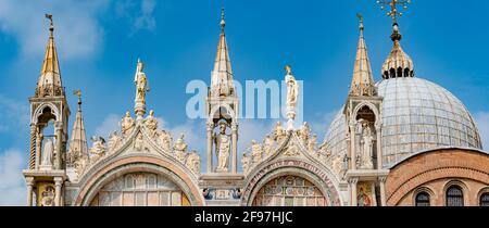 Panoramablick über Dekorationselemente an Dächern und Kuppeln der Basilika San Marco in Venedig, Italien, bei sonnigem Tag und tiefblauem Himmel Stockfoto