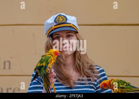 Portrait eines schönen Mädchen, Animator für Touristen mit bunten Papageienvögel in der historischen Innenstadt von Prag, Tschechische Republik, Sommer Stockfoto