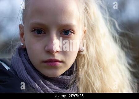 Porträt eines Teenagers mit blonden Haaren in einem frühen Frühlingspark. Hohe Qualität Stockfoto