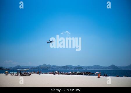 Eine Aufnahme des Atro do Flamengo Beach mit einem Startflugzeug (vom Internationalen Flughafen Antonio Carlos Jobim) in blauem Himmel im Hintergrund. Rio de Janeiro, Brasilien. Aufgenommen mit Stockfoto