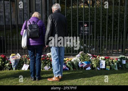 Windsor, Großbritannien. April 2021. Besucher sehen sich Blumengebete an, die von Mitgliedern der Öffentlichkeit vor dem Cambridge Gate im Schloss Windsor am Vorabend der Beerdigung des Herzogs von Edinburgh hinterlassen wurden. Die Beerdigung von Prinz Philip, Königin Elisabeths Ehemann, findet IIÕs 17. April um 15:00 Uhr BST in der St. George's Chapel in Windsor Castle statt. Kredit: Mark Kerrison/Alamy Live Nachrichten Stockfoto