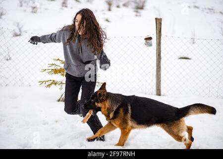 Junge Brünette Mädchen spielt mit ihrem Schäferhund. Winterzeit Stockfoto