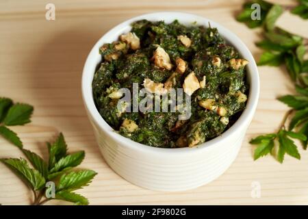 Eine Tasse Pesto aus jungen gemahlenen Holunderblättern - eine wilde essbare Pflanze Stockfoto