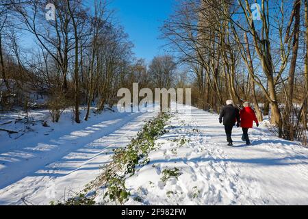 Bochum, Nordrhein-Westfalen, Deutschland - sonnige Winterlandschaft im Ruhrgebiet, Spaziergänger in Eis und Schnee auf dem renaturierten Hofsteder Bach, der Bach wurde in einen natürlichen Wasserkörper verwandelt, der Hofsteder Bach fließt über den Hüller Bach in den Emscher, Gehört zum Emscher- und Flusssystem, so dass für den Emscher-Umbau zuvor ein offener oberirdisch-gerundter Abwasserkanal, Mischwasserkanal mit Oberflächenwasser und Abwasser vorhanden war. Stockfoto