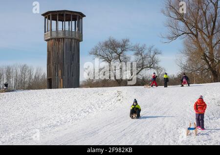 Recklinghausen, Nordrhein-Westfalen, Deutschland - sonnige Winterlandschaft im Ruhrgebiet, Emscherkunst im Schnee, Kawamata Tower auf der Emscher, GEHWEG UND TURM, 2010, von Tadashi Kawamata, Kinder fahren Schlitten. Stockfoto