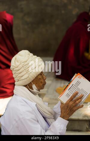 Indien, Bodhgaya, Szenen im Mahabodhi-Tempel, ältere Frau beim Lesen Stockfoto