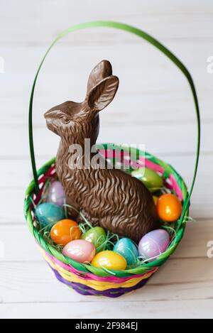 Osterkorb mit Eiern und Schokoladenhase auf weißem Hintergrund. Stockfoto