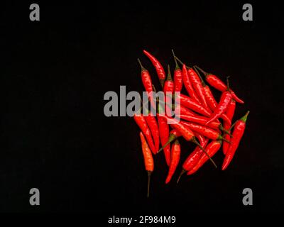 Haufen roter scharfer Chilischoten auf schwarzem Hintergrund, Draufsicht Stockfoto