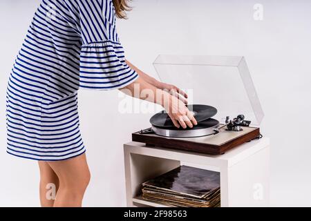 Frau in blau-weiß gestreiftem Kleid gekleidet Putting Music Auf Vinyl Stockfoto