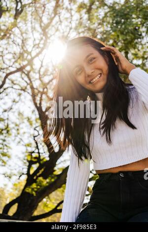 Lächelnde Frau mit herbstlicher Sonneneinstrahlung von hinten. Stockfoto