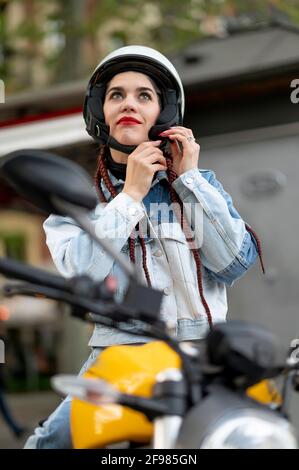 Frontalaufnahme einer jungen Frau, die einen Motorradschutz befestigt Helm Stockfoto