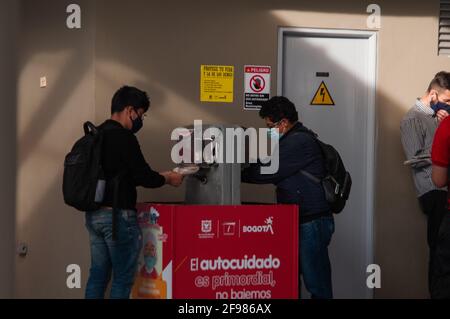 Die Menschen tragen dazu bei, COVID-19-Inffektionen zu vermeiden, indem sie sich die Hände in einem Waschbecken mit dem Büro des Bürgermeisters und den Transmilenio-Logos in Bogota, Kolumbien, waschen Stockfoto