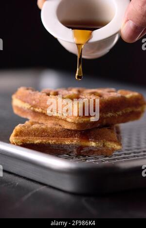 Waffel frisch zubereitet und mit Ahornhonig getaucht Stockfoto