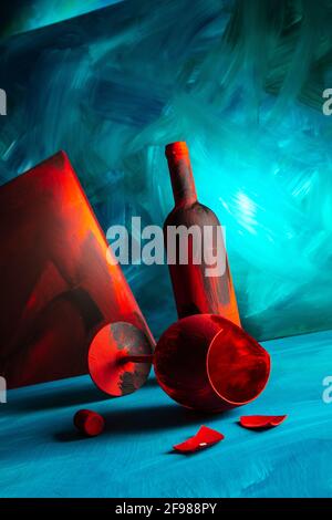 Rot bemalte Weinflasche und Weinglas auf blauem Hintergrund. Stockfoto