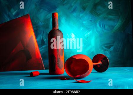 Rot bemalte Weinflasche und Weinglas auf blauem Hintergrund. Stockfoto