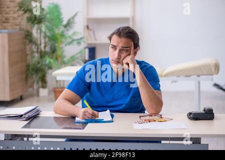 Junger Arzt schreibt Rezept in der Klinik Stockfoto