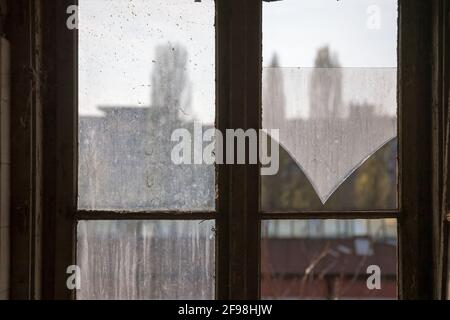 Selektive Unschärfe auf dem zerbrochenen Glas eines kaputten Fensters mit einem Holzrahmen in einem verlassenen und zerstörten privaten Haus und Haus. Bild Stockfoto