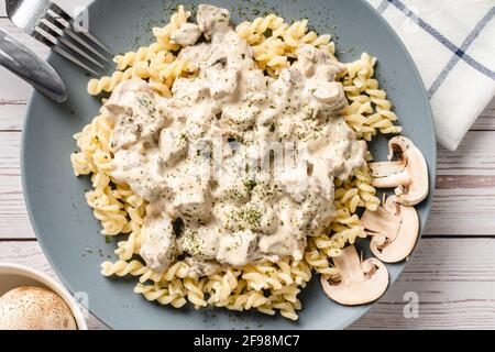 Tagliatelle Italienische Pasta mit Wald weißen Champignon Pilze cremige Sauce Und Huhn oder Rindfleisch - hausgemachte Speisen auf dem Teller Auf der Tischansicht Stockfoto