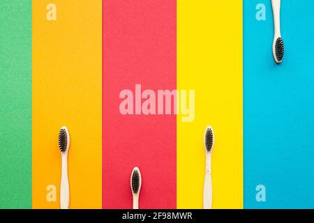 Zusammensetzung von Bio-Bambus-Zahnbürsten auf dem hellen mehrfarbigen Hintergrund. Natürliche Mundhygiene. Zahnschutz ohne Verschwendung. Stockfoto