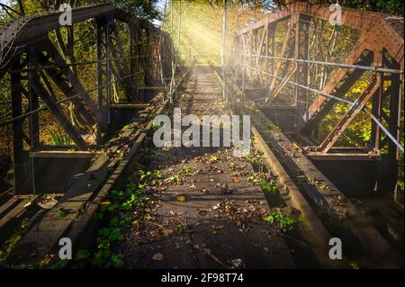 Ausgediente Eisenbahnbrücke in künstlicher Hintergrundbeleuchtung. [M] Stockfoto