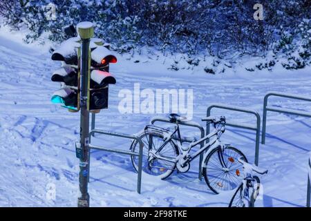 Verschneite Ampeln und geparkte Fahrräder in der Abenddämmerung, Bremen, Deutschland, Europa Stockfoto