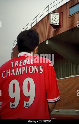 Old Trafford Stadium, Manchester, Großbritannien. 21 Okt 2000. Ruben Setiawan - ein eingefleischter Manchester United-Fan aus Indonesien; einer der Gründer des Indomanutd-Supporterclubs - Er trägt ein personalisiertes Manchester United Trikot und posiert, um fotografiert zu werden, während er die Gedenkstätte der Münchner Luftkatastrophe von Manchester United auf der Oberseite des Old Trafford Stadions überblickt, bevor Manchester United gegen Leeds United in der Saison FA Carling Premiership 2000-01 am 21. Oktober 2000 antrat. Stockfoto