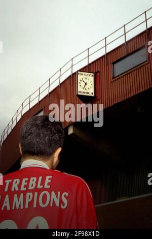 Old Trafford Stadium, Manchester, Großbritannien. 21 Okt 2000. Ruben Setiawan - ein eingefleischter Manchester United-Fan aus Indonesien; einer der Gründer des Indomanutd-Supporterclubs - Er trägt ein personalisiertes Manchester United Trikot und posiert, um fotografiert zu werden, während er die Gedenkstätte der Münchner Luftkatastrophe von Manchester United auf der Oberseite des Old Trafford Stadions überblickt, bevor Manchester United gegen Leeds United in der Saison FA Carling Premiership 2000-01 am 21. Oktober 2000 antrat. Stockfoto