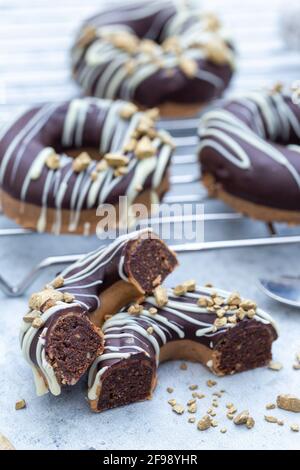 Nahaufnahme einer halbierten appetitlichen Schokolade überzogenen rohen Donuts mit Nüsse bestreuen Stockfoto