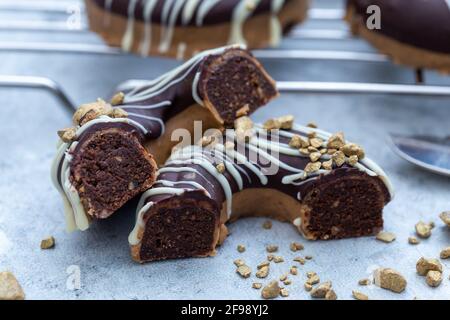 Nahaufnahme einer halbierten appetitlichen Schokolade überzogenen rohen Donuts mit Nüsse bestreuen Stockfoto