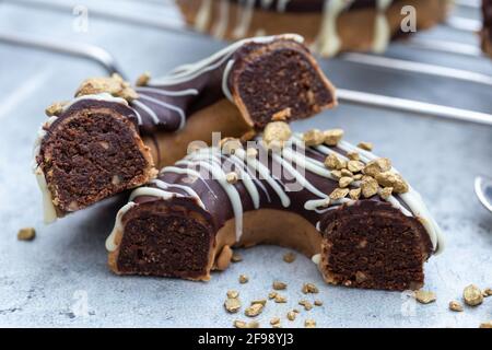 Nahaufnahme einer halbierten appetitlichen Schokolade überzogenen rohen Donuts mit Nüsse bestreuen Stockfoto