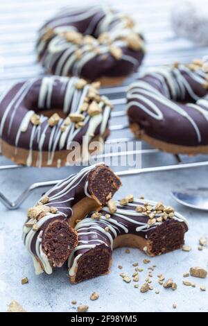 Nahaufnahme einer halbierten appetitlichen Schokolade überzogenen rohen Donuts mit Nüsse bestreuen Stockfoto