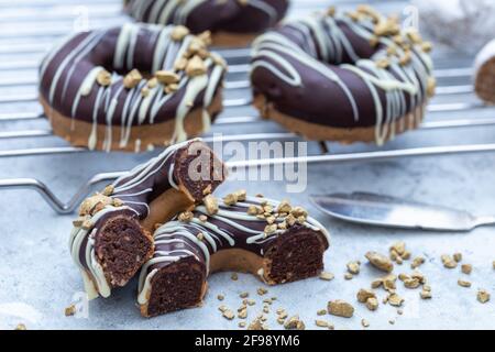 Nahaufnahme einer halbierten appetitlichen Schokolade überzogenen rohen Donuts mit Nüsse bestreuen Stockfoto