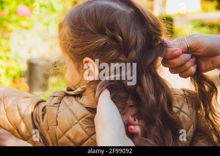 Die Mutter flechtete die Haare ihrer Tochter Stockfoto