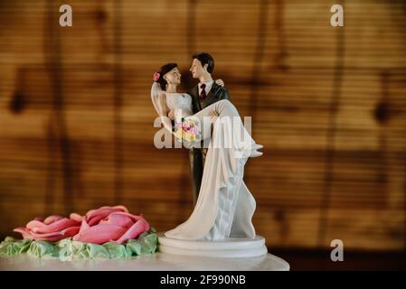 Schöne Figur eines Bräutigams, der eine Braut auf den hebt Hochzeitstorte als Dekoration Stockfoto