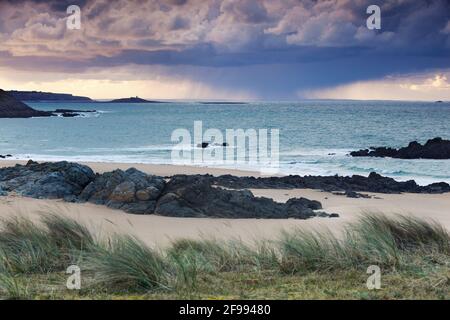 In der Ferne bewegt sich am Pleirel Plage ein Sturm über das Meer, zwischen Cap Frehel und der Gezeiteninsel Ilot Michel. Bretagne, Frankreich Stockfoto