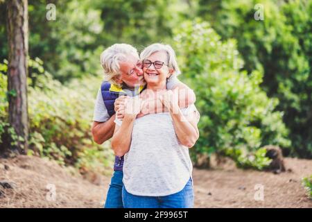 Glück und Liebesbeziehung. Paar alte Menschen Mann und Frau Senior Schwein und Kuss im Outdoor-Park - ältere Rentner Lebensstil und fröhlich - Konzept der zusammen für immer und Freizeit im Freien Stockfoto