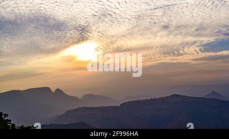 Spektakulärer Blick auf die Silhouette während des Sonnenuntergangs in der Sahyadri-Bergkette an einem Winterabend vom Sunset Point in Matheran, Maharashtra, Indien. Stockfoto