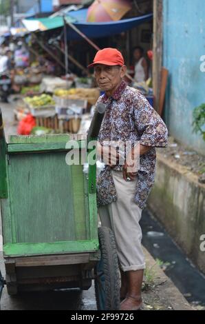 Jakarta, Indonesien April 08 2021: Ein alter Mann steht vor seinem Wagen. Stockfoto