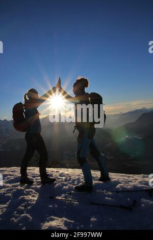 Winterwanderung zum Signalkopf (1895 Meter) Sonnenuntergang mit Blick auf das Wettersteingebirge, 2 junge Frauen klatschen, klatschen, Europa, Deutschland, Bayern, Oberbayern, Isartal, Krün Stockfoto