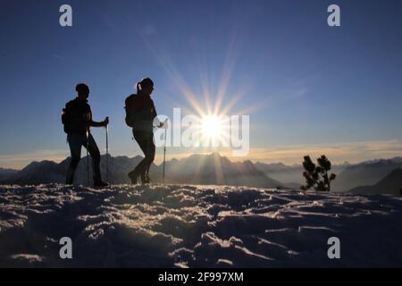 Zwei junge Frauen bei Sonnenuntergang, Winterwanderung zum Signalkopf (1895 Meter) mit Blick auf den Wettersteingebirge, Zugspitze, Europa, Deutschland, Bayern, Oberbayern, Isartal, Krün Stockfoto